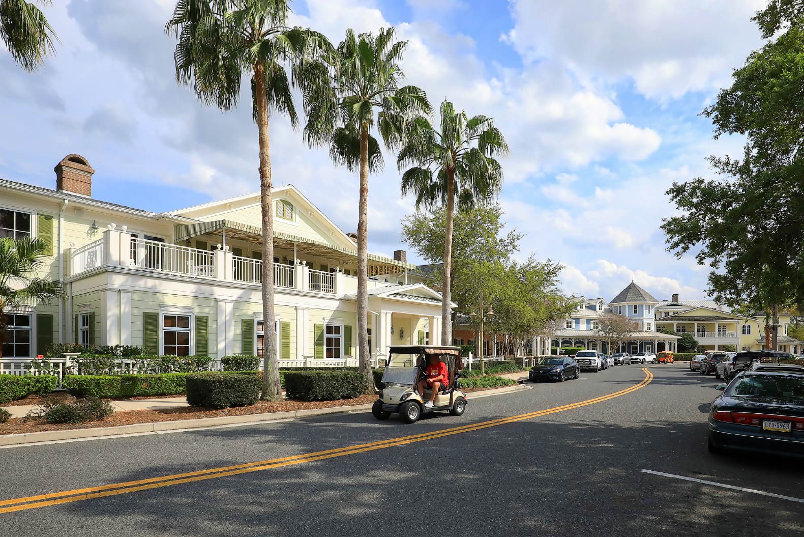 Someone drives a golf cart down the street in front of houses at The Villages.